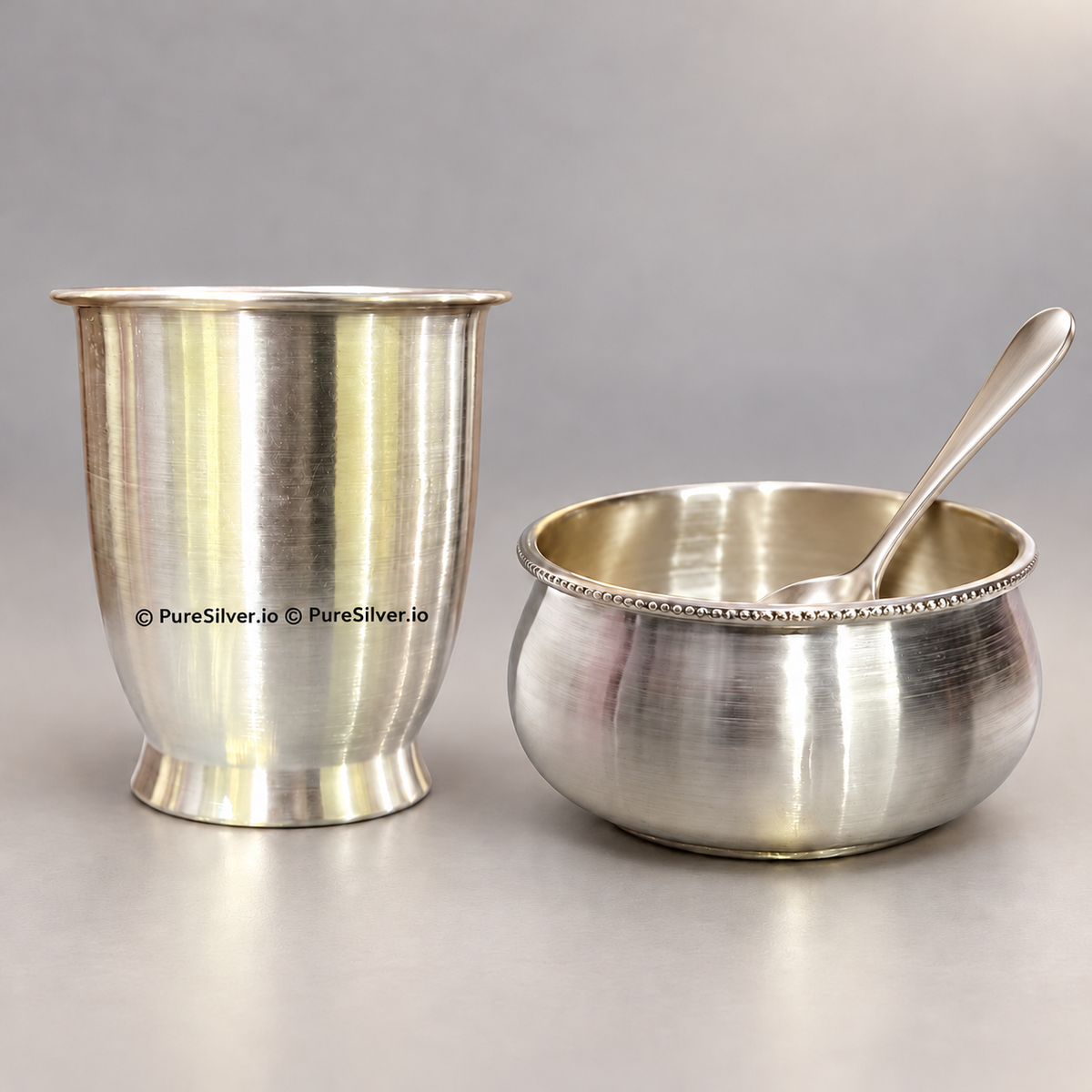 999 silver glass and bowl with a matching plain spoon resting inside the bowl